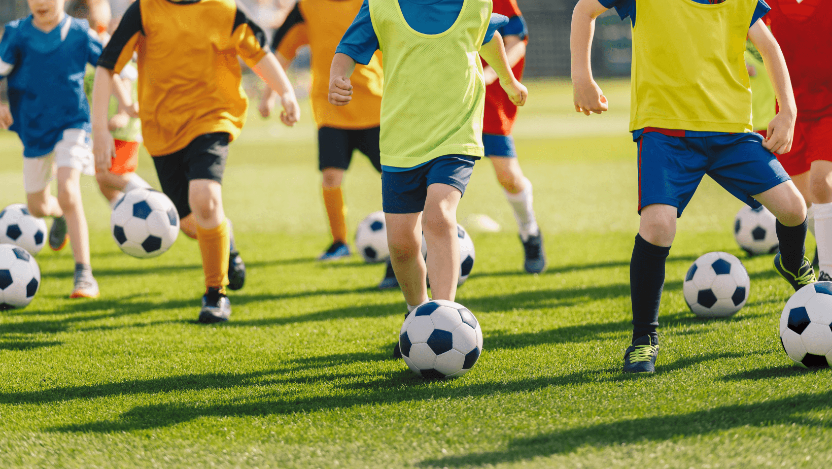 Young players training and dribbling on a football pitch